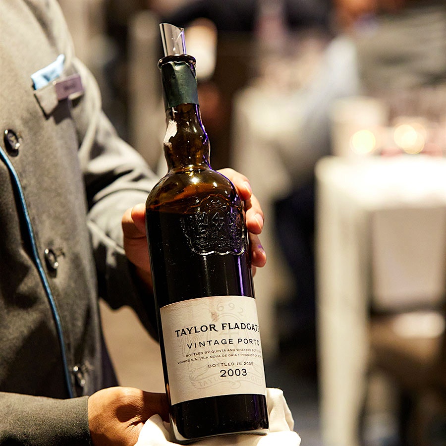 A member of Wine Experience staff holding a bottle of Taylor Fladgate Vintage Port 2003
